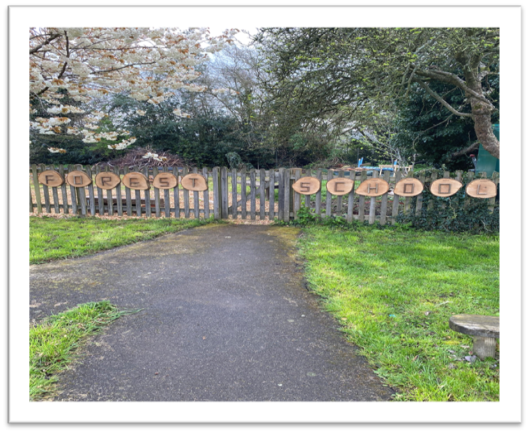 Fence with tree trunks spelling out forest school