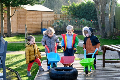 Children playing with plastic wheel barrows in the garden