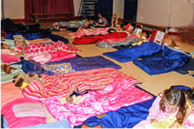 children in sleeping bags in the school hall